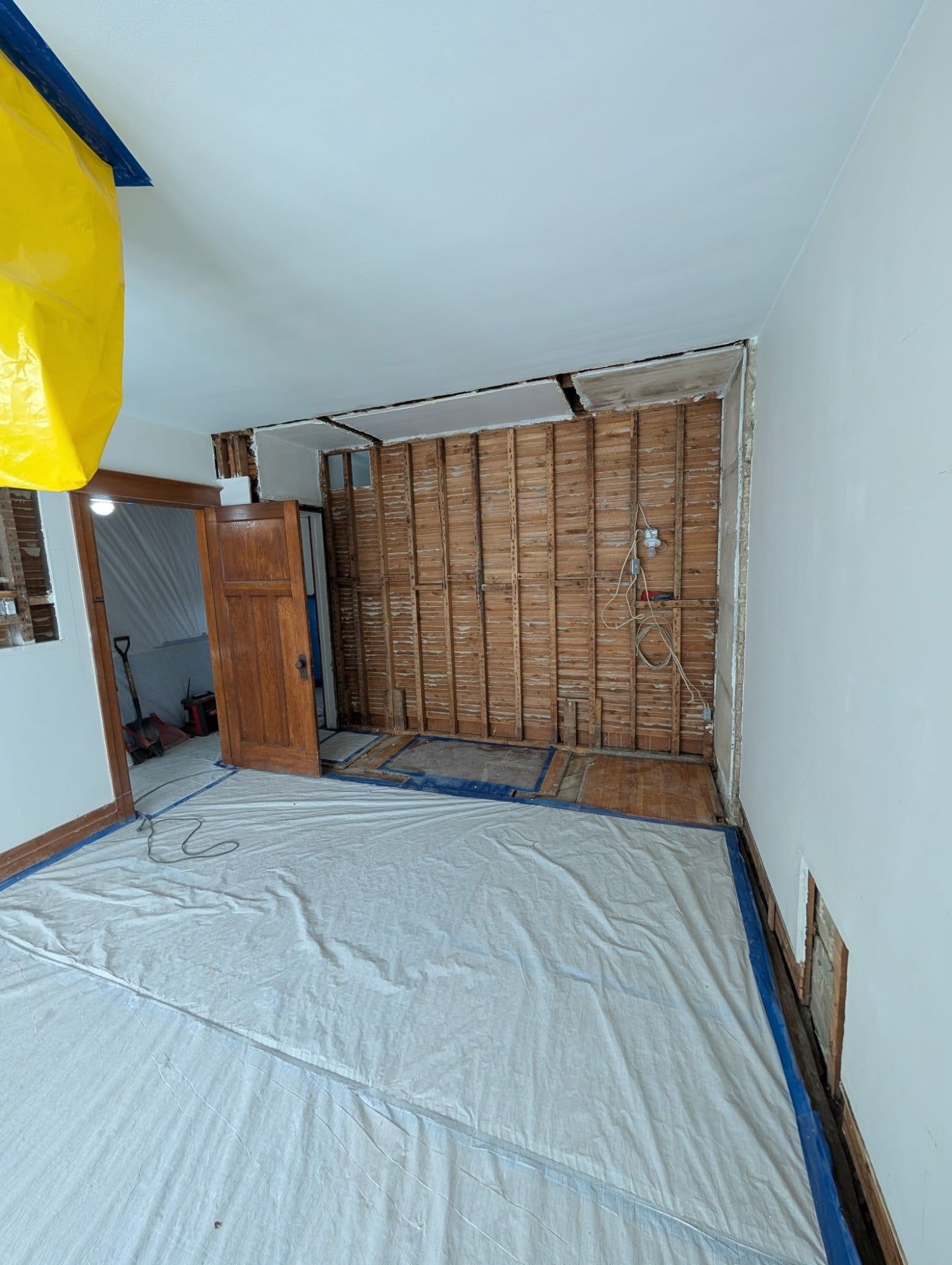 Mur ouvert jusqu'au lattis de bois, plancher protégé au polyéthylène