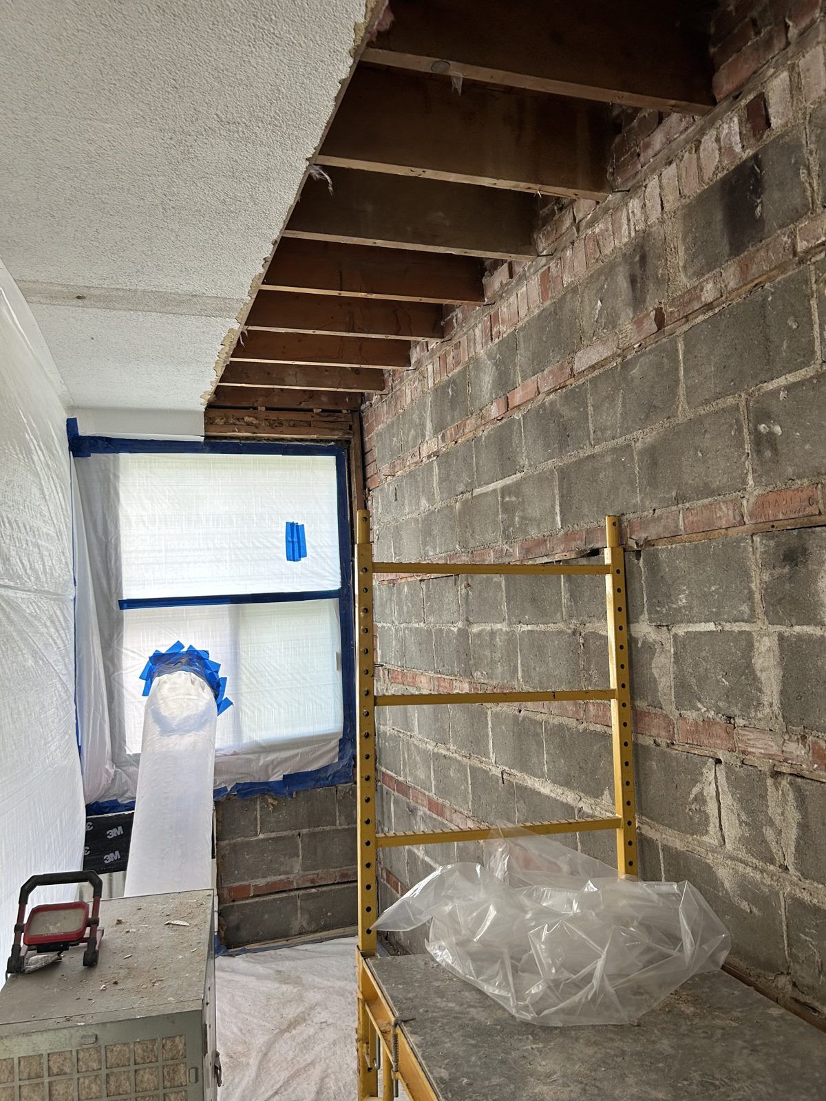 Aire confinée : plafond texturé ouvert jusqu'aux solives, extracteur HEPA et échafaudage